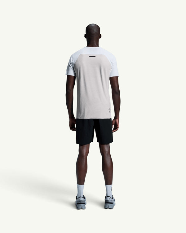 Back view of a man wearing an On performance running tee in light grey with black athletic shorts.
