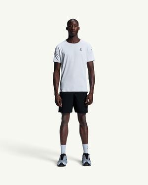 On men's white performance running t-shirt with athletic cut, worn by a model with black shorts and sneakers.