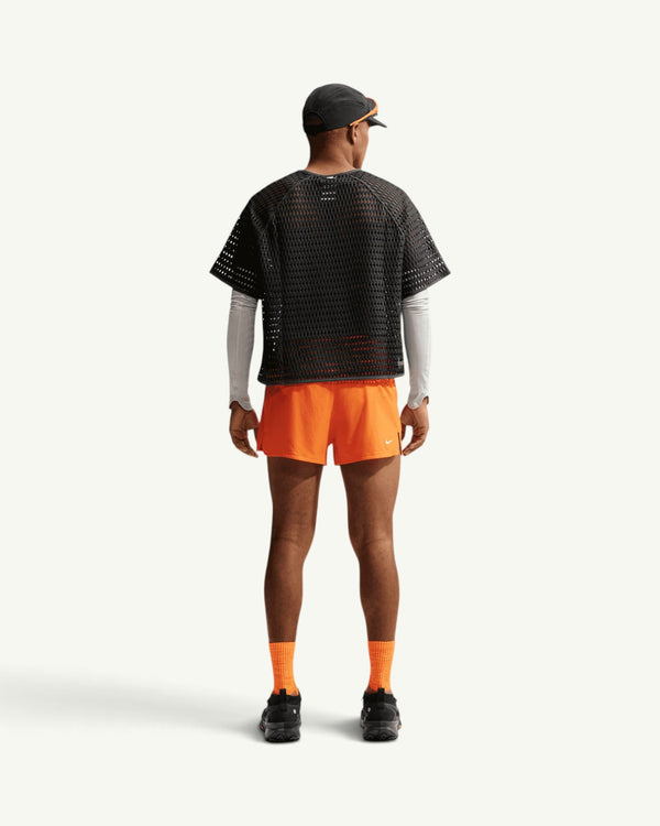 Nike ACG men's black open-hole mesh airflow short sleeve top worn by a runner from the back view