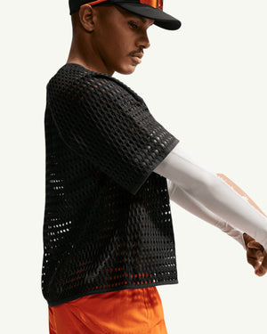 Nike ACG Men's Radical Airflow short sleeve top in black open-hole knit fabric worn by a male athlete on a trail.