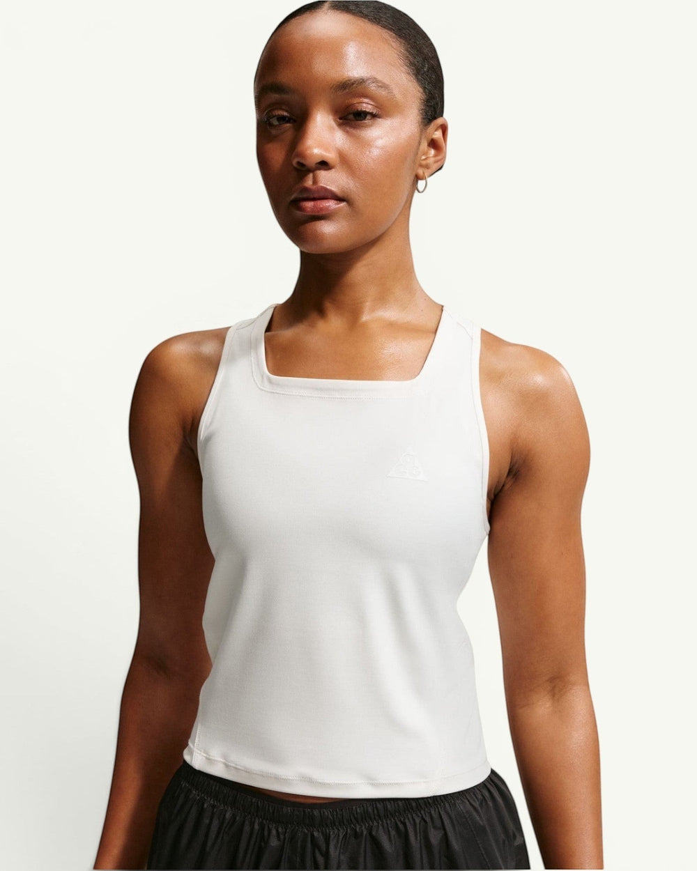 Amateur women's white Dri-FIT trail running tank top with a racerback design and reflective logo detail.