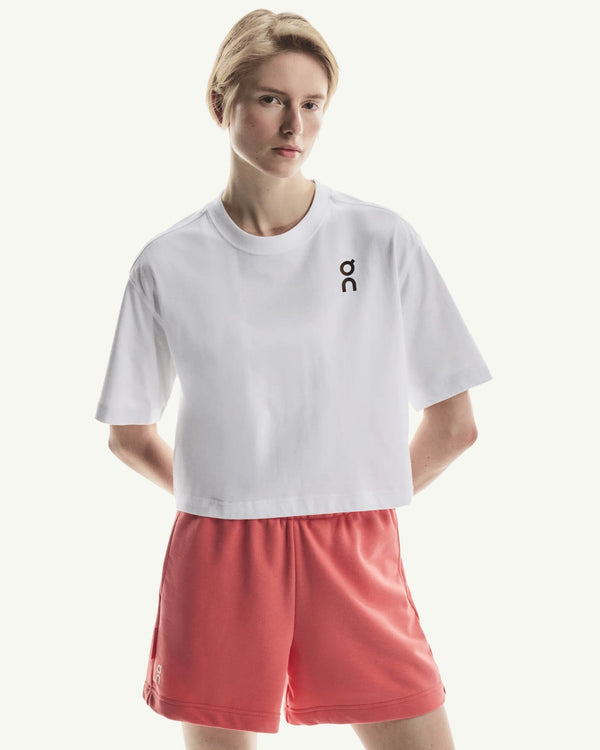 On women's white boxy-cut cotton-blend t-shirt with short sleeves and a small black logo on the chest