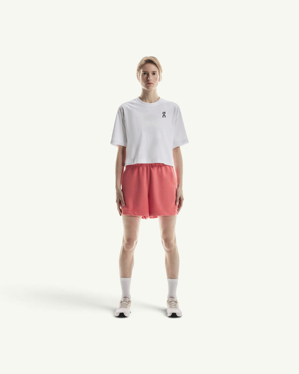 On women's white boxy cotton-blend t-shirt paired with coral athletic shorts on a model