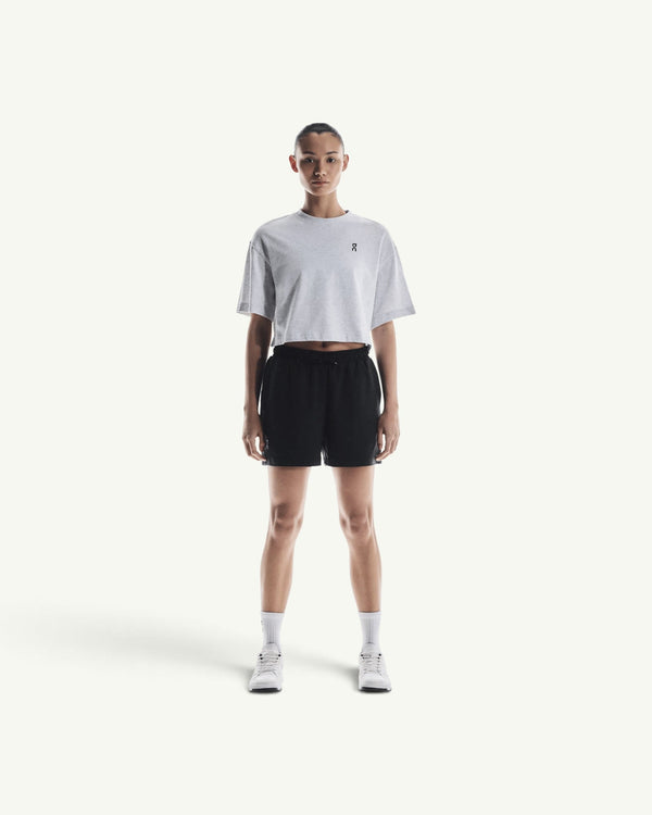 On Women's Club boxy-fit grey cotton-blend t-shirt worn with black athletic shorts and white sneakers