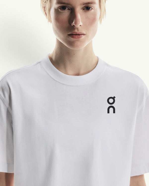 On women's white boxy-fit cotton-blend t-shirt with a black logo on the chest worn by a model