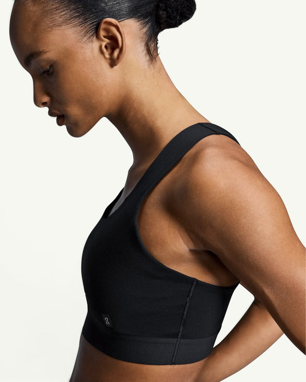 On Women's Core Bra in black, featuring a seam-minimal design for light-to-medium support on a model.