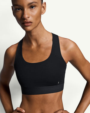 On women's black core sports bra with a racerback design, offering light-to-medium support for daily activities.