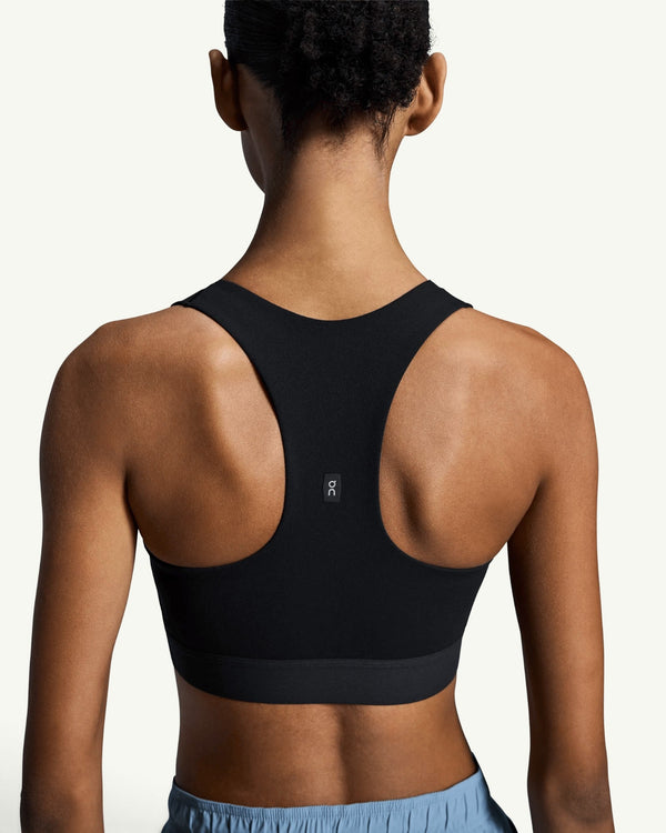 Back view of a woman wearing a black On Women's Core Bra with a racerback design for light-to-medium support.
