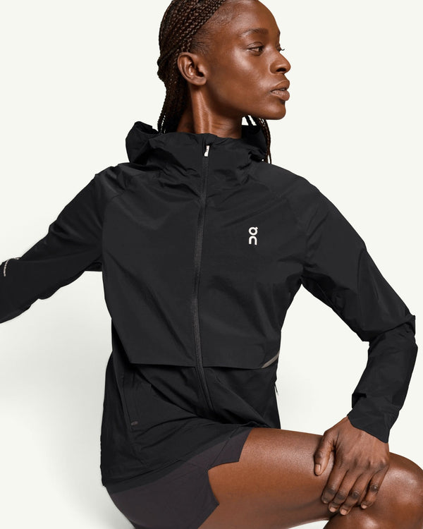 On women's black lightweight wind-blocking running jacket with a hood and front zipper