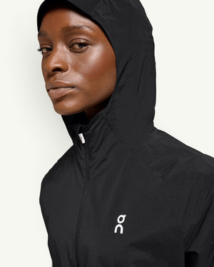 On women's black lightweight hooded running jacket with wind-blocking shell and white logo detail