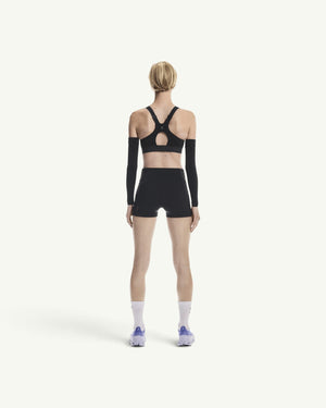 On women's black performance sports bra with racerback design, worn by a model from the back view.