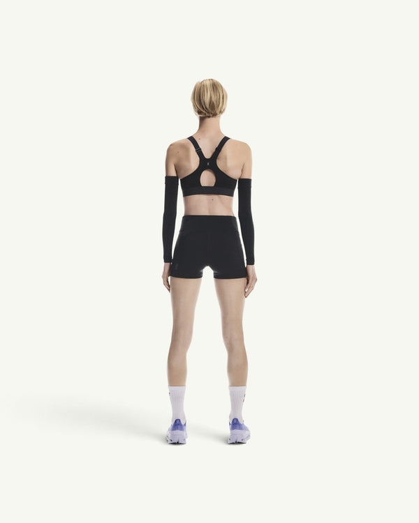 On women's black performance sports bra with racerback design, worn by a model from the back view.