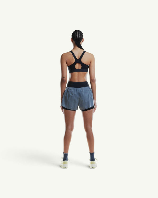 On women's black performance sports bra with a racerback design, worn by a model from the back view.
