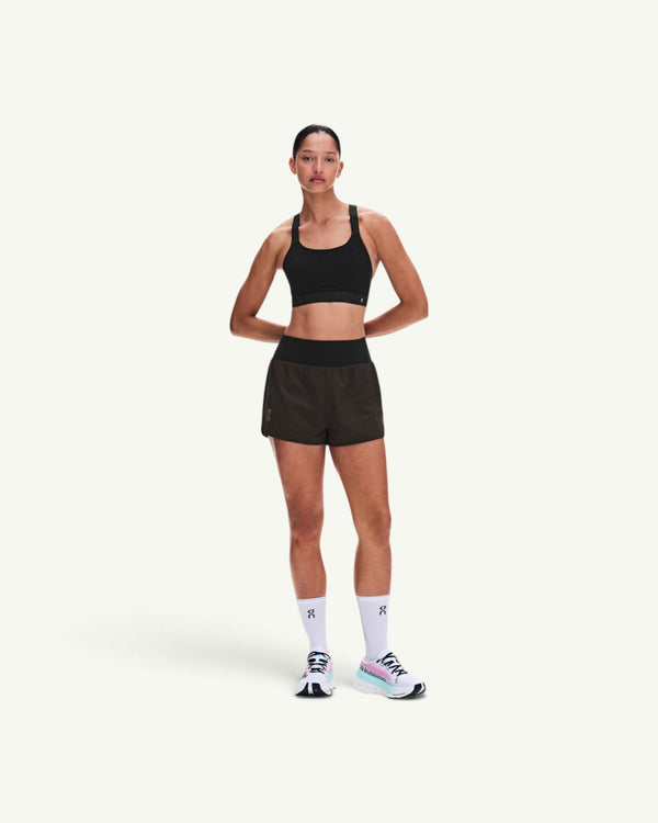 On women's black performance running shorts with a high waistband, worn by a model with a matching sports bra.