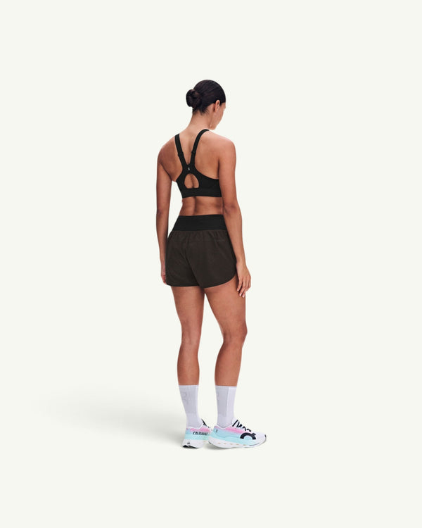 On women's black performance running shorts with a high waistband, worn by a runner from a rear view.