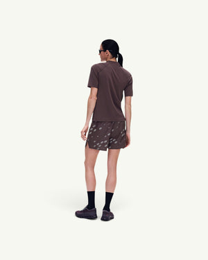 On women's brown short-sleeve trail tee with UV protection, worn with patterned shorts, back view.