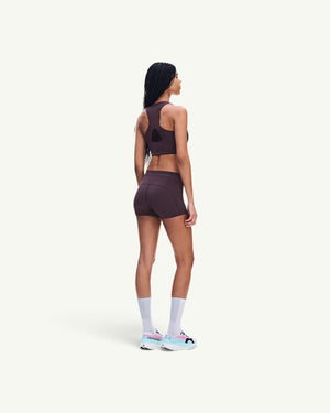 On women's dark brown ultralight short tights with minimal seams, worn by a model from a side-back view.