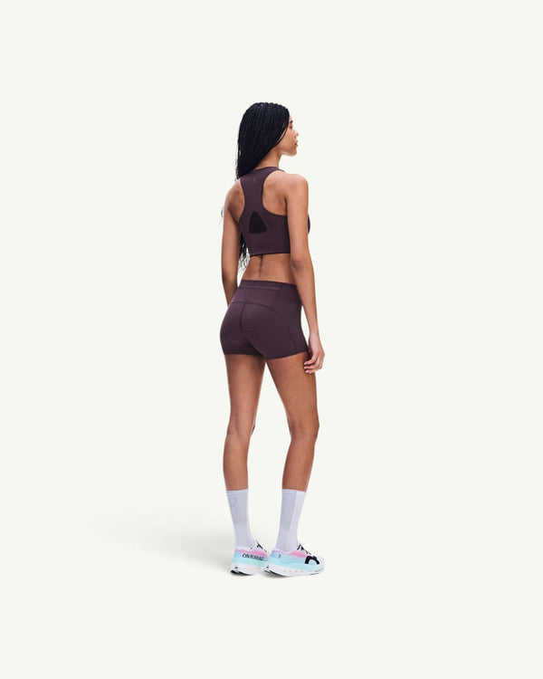 On women's dark brown ultralight short tights with minimal seams, worn by a model from a side-back view.