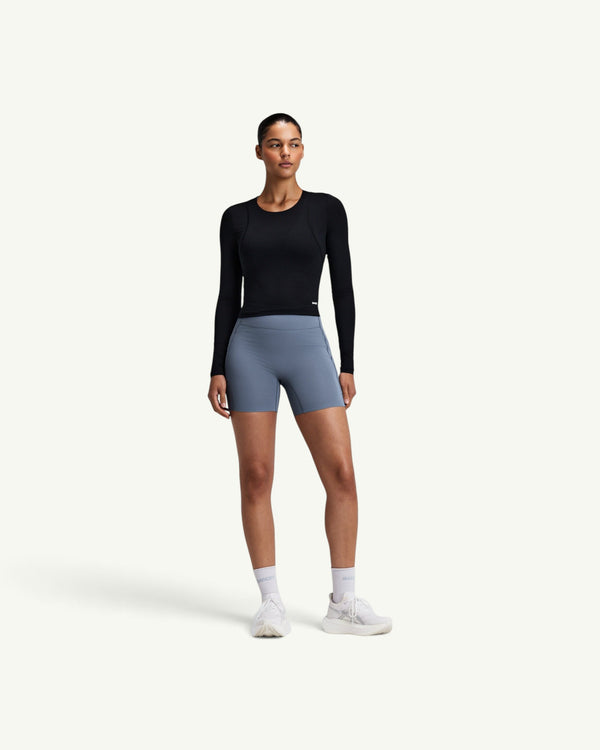 Amateur black GeoMesh performance long sleeve top with bonded seams worn by a model with blue athletic shorts.