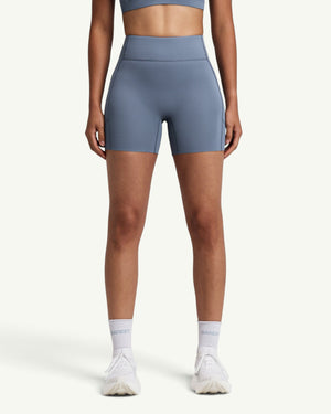 Amateur women's blue high-waist compression shorts with side pockets and grip hem, front view.