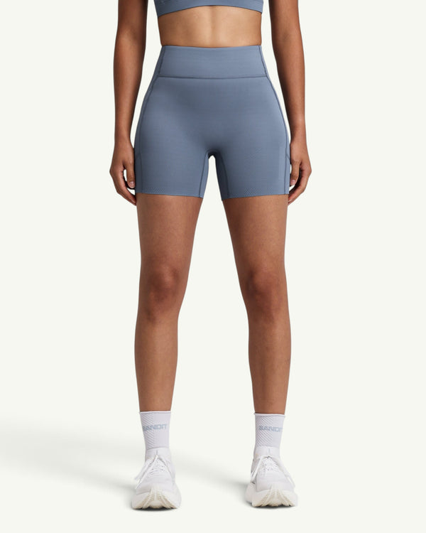 Amateur women's blue high-waist compression shorts with side pockets and grip hem, front view.