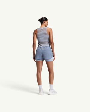 Amateur women's CoolGrid race singlet in light grey with shadow-stripe knit, worn with blue athletic shorts from behind