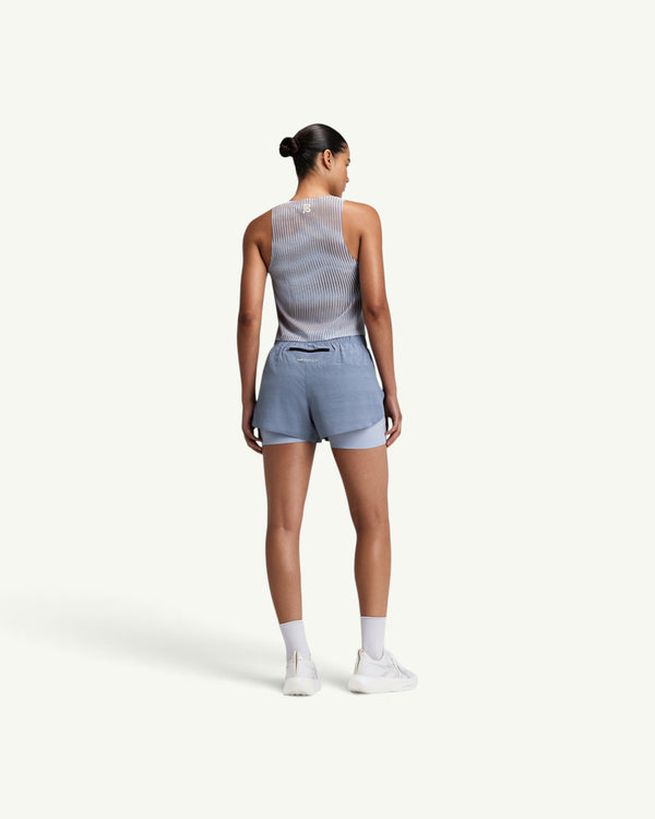 Amateur women's CoolGrid race singlet in light grey with shadow-stripe knit, worn with blue athletic shorts from behind