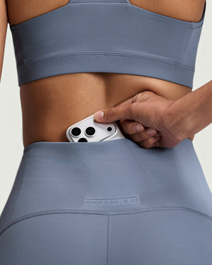 Amateur high-waist compression shorts in slate blue with a hidden centre-back phone pocket and embossed branding.