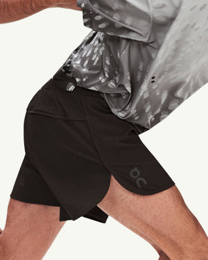 Amateur men's black performance running shorts with side slits and logo detail worn by a runner in motion
