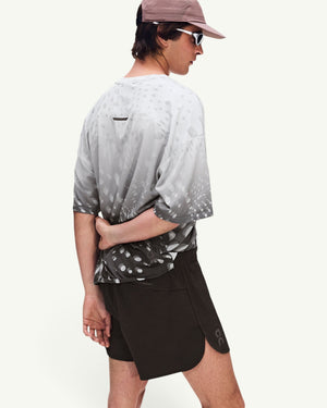 Amateur men's black performance shorts with side slits and logo detail worn by a model in a patterned grey shirt