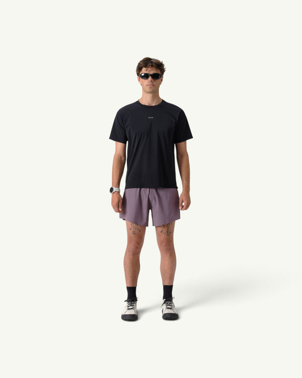 Amateur men's black thermal dispersion trail tee worn by a model with purple shorts and athletic gear