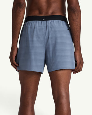 Back view of Amateur MEN'S COOLGRID 5 inch blue running shorts with a black waistband on a male model