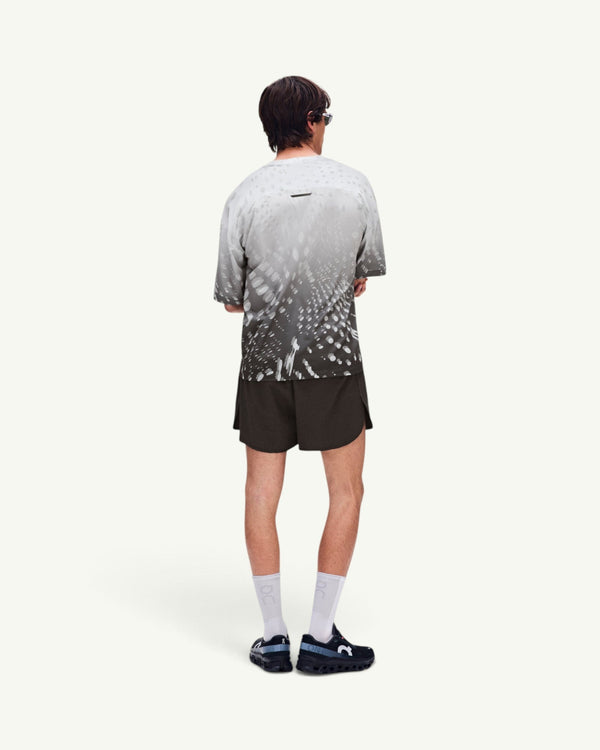Amateur men's performance volt shorts in dark grey, worn by a model with a patterned t-shirt and athletic sneakers.