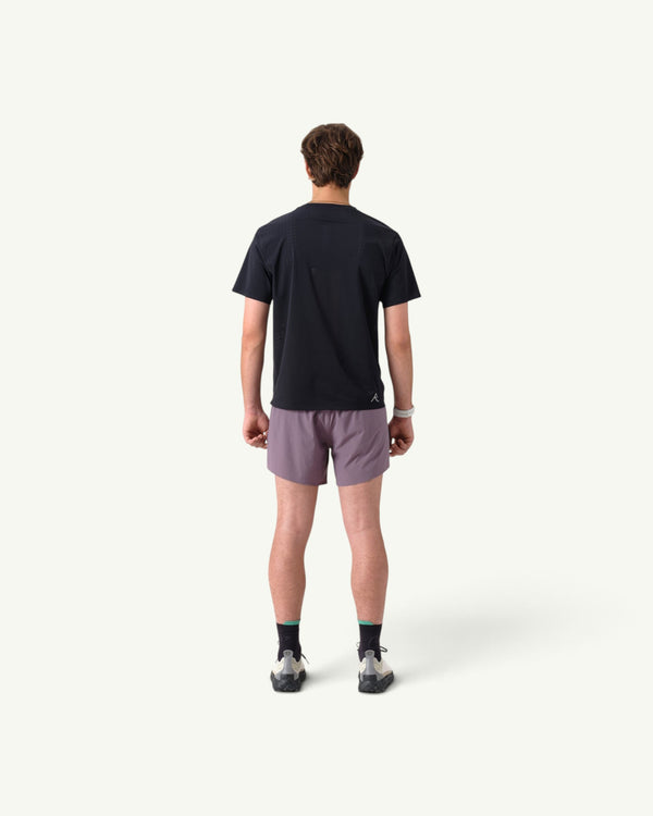 Amateur men's black thermal dispersion trail tee worn from the back with grey athletic shorts and trail shoes.