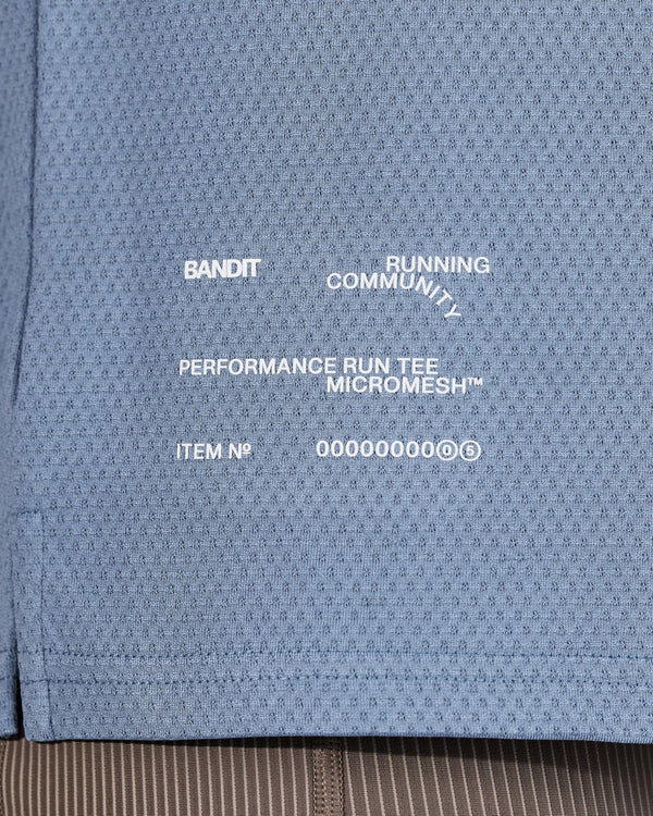 Close-up of Amateur MEN'S MICROMESH™ RUN TEE in blue, featuring white printed branding and technical mesh fabric.