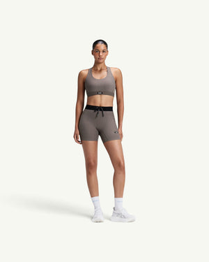 Amateur women's ribbed scoop neck T-back run bra in taupe, paired with matching compression shorts on a model.