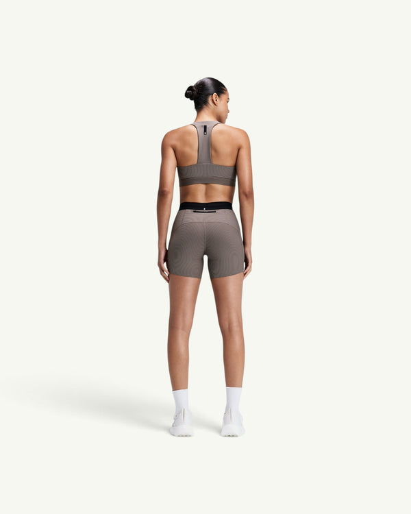 Amateur women's taupe ribbed T-back sports bra and matching compression shorts worn by a model from the back view.