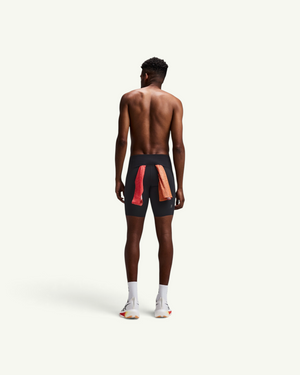 Amateur men's black compression half tights with red mesh detailing on the back, worn by a runner from behind.