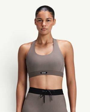 Amateur women's taupe ribbed scoop neck T-back sports bra with compression fit and Bandit logo patch
