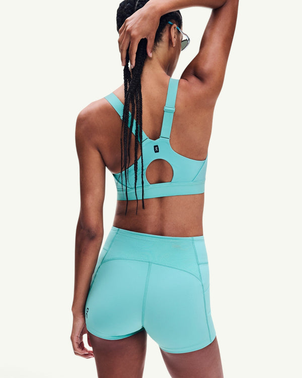 Amateur women's turquoise performance tights and matching sports bra worn by a model, back view