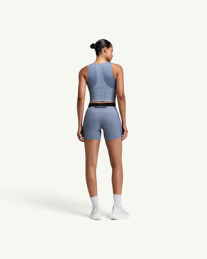 Amateur women's blue square neck race crop top with GeoMesh back panel and storage pockets, worn with matching shorts.