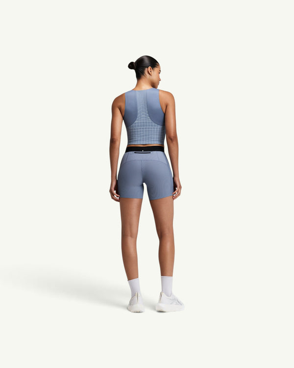 Amateur women's blue square neck race crop top with GeoMesh back panel and storage pockets, worn with matching shorts.