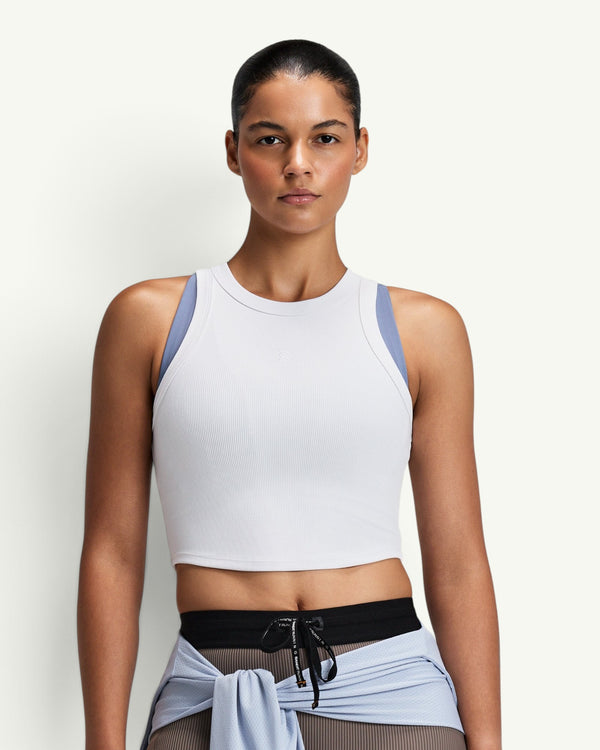Amateur women's white ribbed performance tank top with a cropped fit and moisture-wicking fabric on a model.