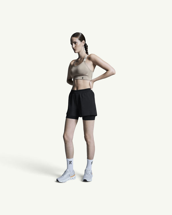Amateur women's black 3-inch 2-in-1 performance running shorts with supportive inner tights on a female athlete.