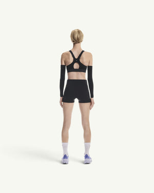 Back view of a woman wearing Amateur black 3-inch performance running shorts with a matching sports bra and arm sleeves