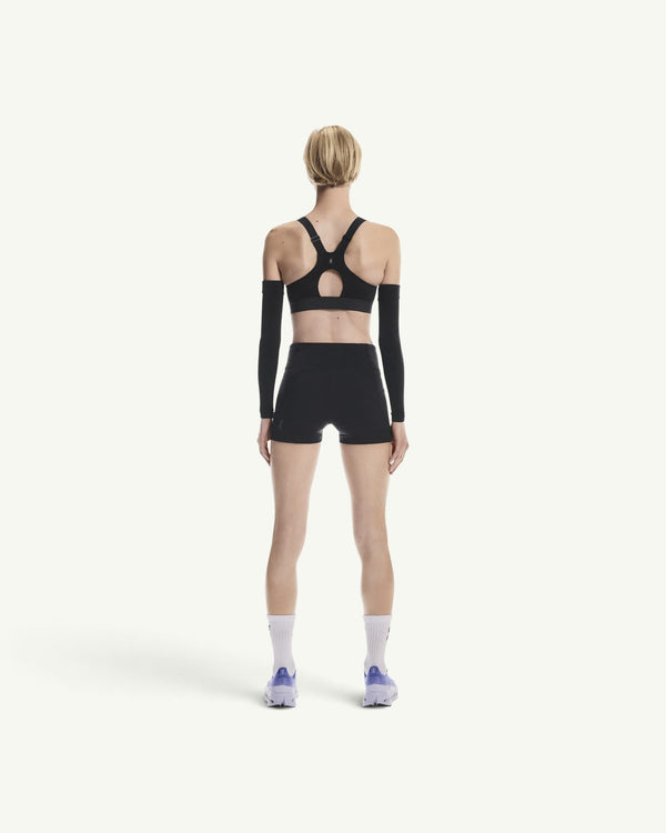 Back view of a woman wearing Amateur black 3-inch performance running shorts with a matching sports bra and arm sleeves