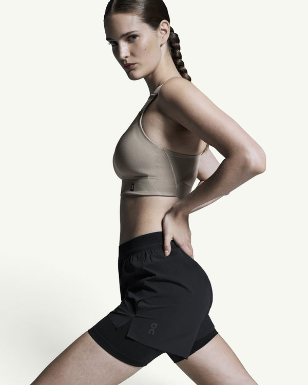 Amateur women's black 3-inch performance 2-in-1 running shorts with supportive inner tight worn by a female athlete