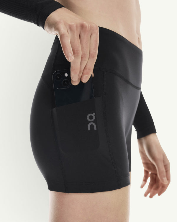 Amateur women's black 3-inch performance running tights featuring a side pocket holding a smartphone