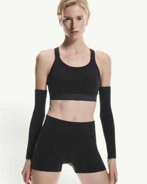 Amateur women's black 3-inch performance tights and matching sports bra with arm sleeves on a model