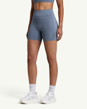 Amateur women's blue high-waist compression shorts with side pockets and grip hem, worn by a runner.